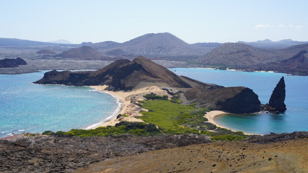 A breathtaking vista of the Galapagos featuring the iconic Pinnacle Rock (right), as seen from the summit of Bartolome Island.