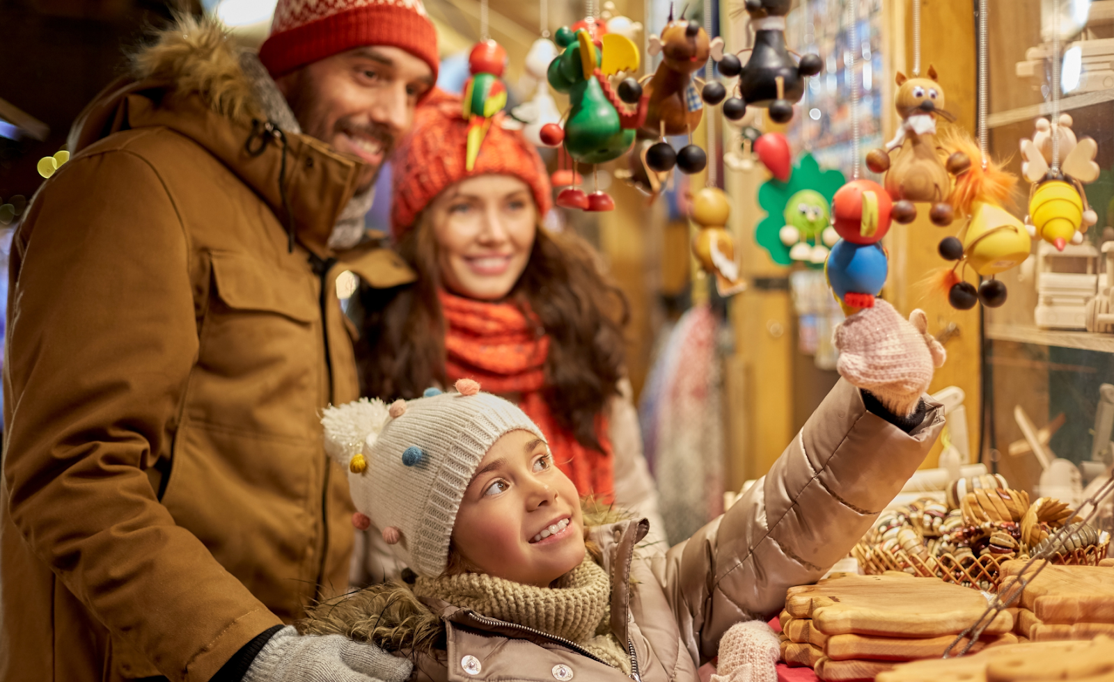 Family of three choosing souvenirs from a stall in a Slovakian Christmas Market.
